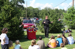 Mark Clark performing his magic show for a group of children at a picnic.